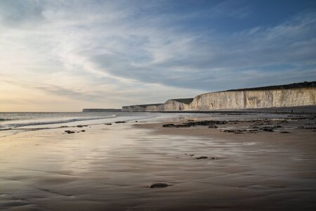 Beautiful landscape image of white chalk cliffs with colorful vibrant sunset on English coastの写真素材