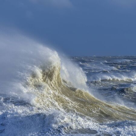 Stunning image of individual wave breaking and cresting during violent windy storm with superb wave detailの写真素材
