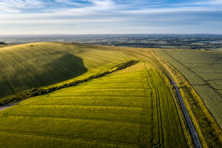 Beautiful high flying drone landscape image of rolling hills in English countryside with lovely warm lightの写真素材