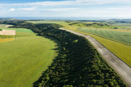 Beautiful high flying drone landscape image of rolling hills in English countryside with lovely warm lightの写真素材