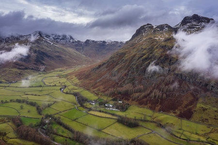 Epic flying drone landscape image of Langdale pikes and valley in Winter with low level clouds and mist swirling aroundの素材 [FY310161699862]