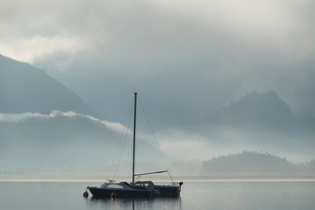Beautiful calm image of sailing boat on Derwentwater in Lake District on a Winter morningの写真素材
