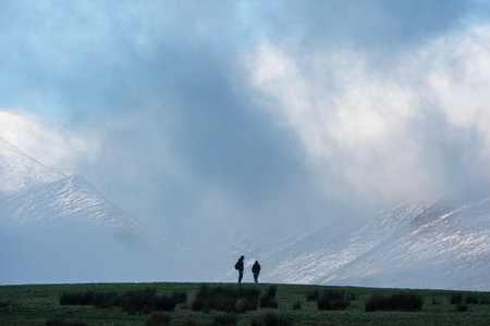 Stunning landscape image of Skiddaw snow capped mountain range in Lake District in Winter with low level cloud around peaksの写真素材