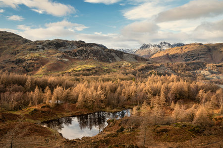 Epic Winter landscape image view from Holme Fell in Lake District towards snow capped mountain ranges in distance in glorious evening lightの写真素材