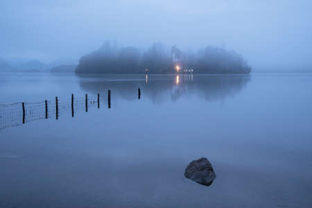 Beautiful landscape image of misty Derwentwater in Lake District on cold Winter morning