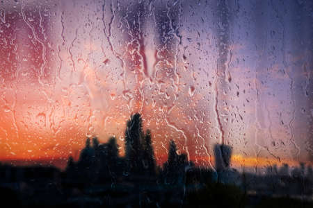 Beautiful landscape conceptual view of London City through glass window with raindrops running down...