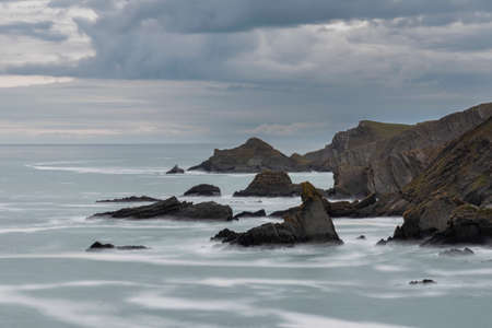 Beautiful fine art landscape image of view from Hartland Quay in Devon England durinbg moody Spring sunsetの写真素材