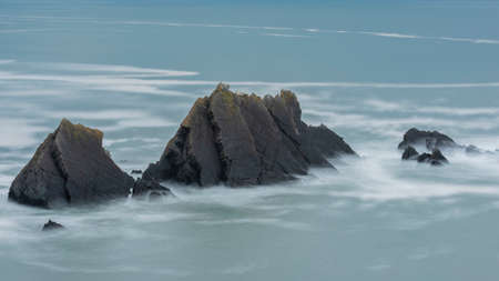 Beautiful fine art landscape image of view from Hartland Quay in Devon England durinbg moody Spring sunsetの写真素材