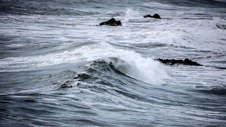 Stunning dark moody toned fine art seascape image of breaking waves on Atlantic Ocean in Devon...