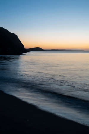 Stunning sunrise over Pentewan Sands in Cornwall with vibrant sky and long exposure oceanの写真素材