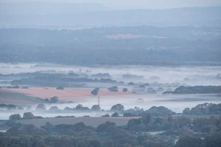 Stunning foggy morning landscape image looking across fields on the South Downs National Park in rolling English contryside during late Summerの写真素材