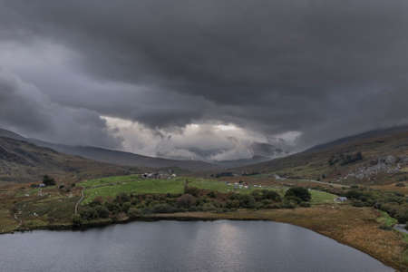 Epic aerial flying drone landscape image towards Crimpiau viewed from above Llynau Mymber during Autumn sunsetの写真素材