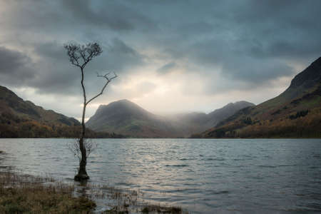 Stunning Autumn sunrise landscape image of Buttermere in Lake District with dramatic stormy skyの写真素材