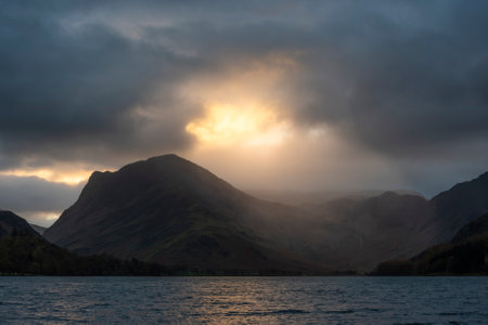 Stunning Autumn sunrise landscape image of Buttermere in Lake District with dramatic stormy skyの写真素材