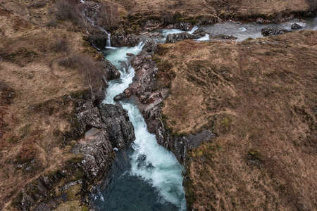 Beautiful aerial drone landscape image of vibrant River Coe flowing beneath snowcapped mountains in Scottish Highlandsの写真素材