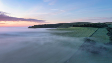 Beautiful drone landscape image of sea of fog rolling across South Downs English countryside during Spring sunriseの写真素材