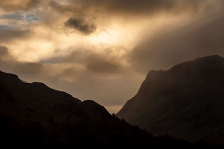 Stunning Autumn sunrise landscape image of Buttermere in Lake District with dramatic stormy sky