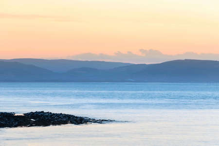 Beautiful landscape image of pastel color sunset over ocean giving lovely soft dreamy relaxing feel