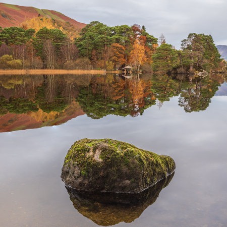Stunning Autumn landscape sunrise image looking towards Catbells from Manesty Park in Lake District with mist rolling across the landscapeの写真素材