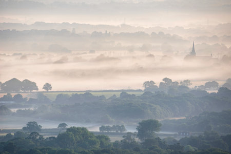 Stunning landscape image of layers of mist rolling over South Downs National Park English countryside during misty Summer sunriseの写真素材