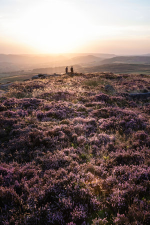 Absolutely stunning sunset landscape image with unidentified couple looking from Higger Tor in Peak...