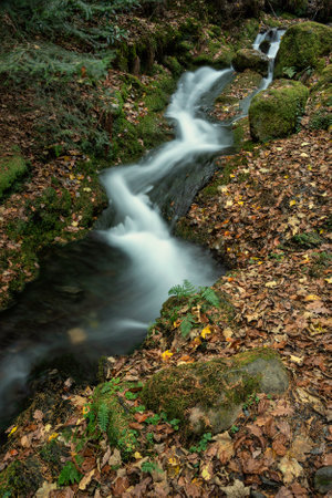 Beautiful waterfall landscape image in vibrant Autumn woodland in Lake Districtの写真素材