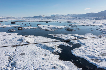 Stunning aerial drone Winter landscape images of Loch Ba and snow covered mountains in background in Scottish Highlandsの写真素材