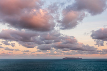 Stunning sunrise clouds formations and colour over Lundy Island on Devonshire coast in England during late Summerの写真素材