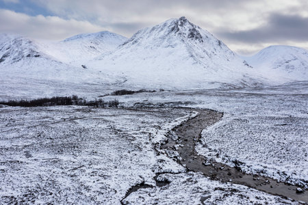 Stunning aerial drone landscape image of Stob Dearg and Glencoe in Scottish Highlands during deep snowfall and beautiful blue skiesの写真素材
