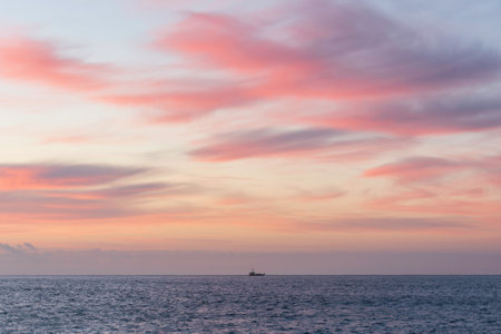 Single fishing trawler boat goes out at sunrise with beautiful colors and clouds formations in Cornwall Englandの写真素材