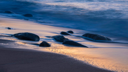 Beautiful landscape of Sennen Cove in Cornwall during sunset with moody sky and long exposure sea motionの写真素材