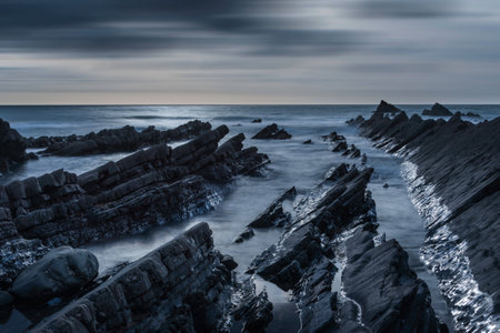 Stunning sunset landscape image of Welcome Mouth Beach in Devon England with beautiful rock formationsの写真素材