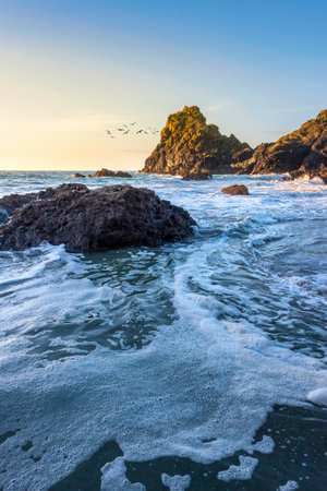Stunning sunrise over Kynance Cove landscape in Corwnall England with vibrant sky and beautiful turquoise oceanの写真素材