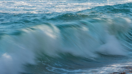 Powerful large turquoise colored waves crashing at Sennen Cove in Cornwall during late sunsetの写真素材