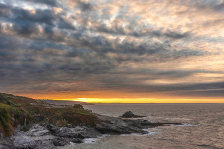 Moody landscape sunrise image at Prussia Cove in Cornwall England with atmospheric sky and ocean