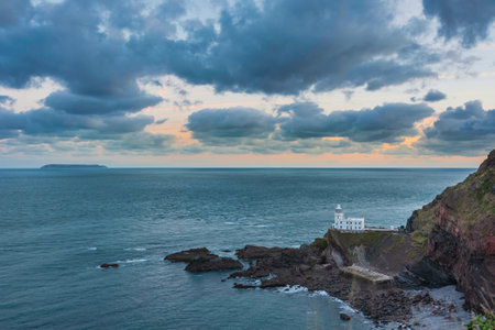 Beautiful sunrise landscape image of Devon coastline in England with stunning golden hour light on the land and skyの写真素材