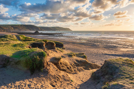 Beautiful Summer sunset landscape image of Widemouth Bay in Devon England with golden hour light on beachの写真素材
