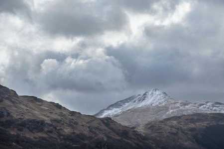 Lovely landscape image of snowcapped Ben Lomond mountain peak in Scottish Highlands with dramatic sky aboveの写真素材