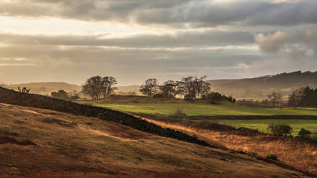 Stunning Winter sunset golden hour landscape image of view from Wast Water over countryside in Lake...