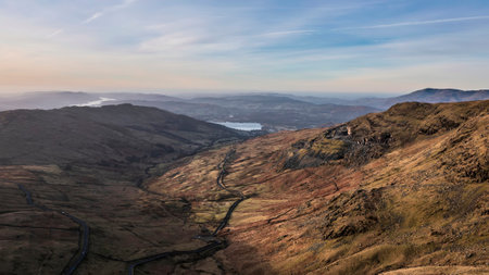 Aerial drone landscape image of sunrise Winter view from Red Screes in Lake District looking towards Windermere in the distance over Wansfell Pike peakの写真素材