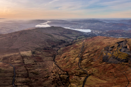 Aerial drone landscape image of sunrise Winter view from Red Screes in Lake District looking towards Windermere in the distance over Wansfell Pike peakの写真素材