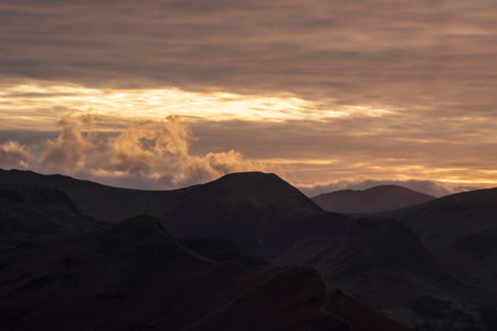 Absolutely stunning landscape image of view across Derwentwater from Latrigg Fell in lake District during Winter beautiful colorful sunsetの写真素材