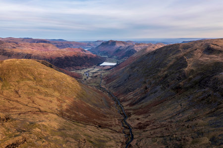 Aerial drone landscape image of sunrise Winter view from Red Screes in Lake District looking towards Brothers Water and Ullswater in the distance over mountain peaksの写真素材