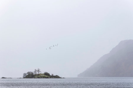 Beautiful Winter sunrise landscape over Ullwater in English Lake District with mist over lake giving a moody dramatic feelの写真素材