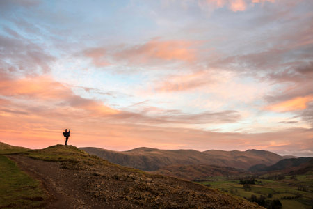 Wonderful sunset landscape image of view from Latrigg Fell towards Great Dodd and Stybarrow Dodd in Lake District with man photographing the landscapeの写真素材