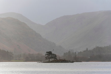 Beautiful Winter sunrise landscape over Ullwater in English Lake District with mist over lake giving a moody dramatic feelの写真素材