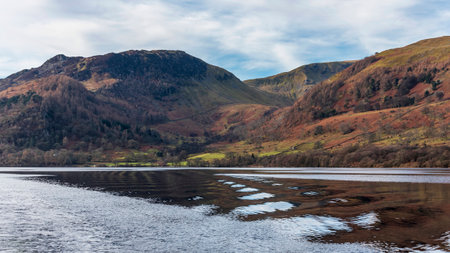 Beautiful Winter landscape image viewed from boat on Ullswater in Lake District with unusual water ripple wake movementsの写真素材