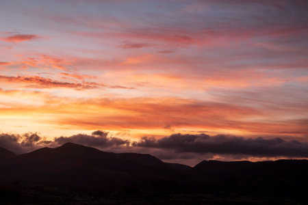 Absolutely stunning landscape image of view across Derwentwater from Latrigg Fell in lake District during Winter beautiful colorful sunsetの写真素材
