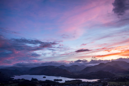 Absolutely stunning landscape image of view across Derwentwater from Latrigg Fell in lake District during Winter beautiful colorful sunsetの写真素材