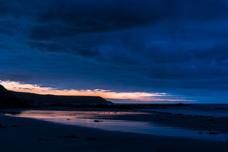 Absolutely stunning sunrise landscape image of Kennack Sands in Cornwall UK wuth dramatic moody clouds and vibrant sunburstの写真素材